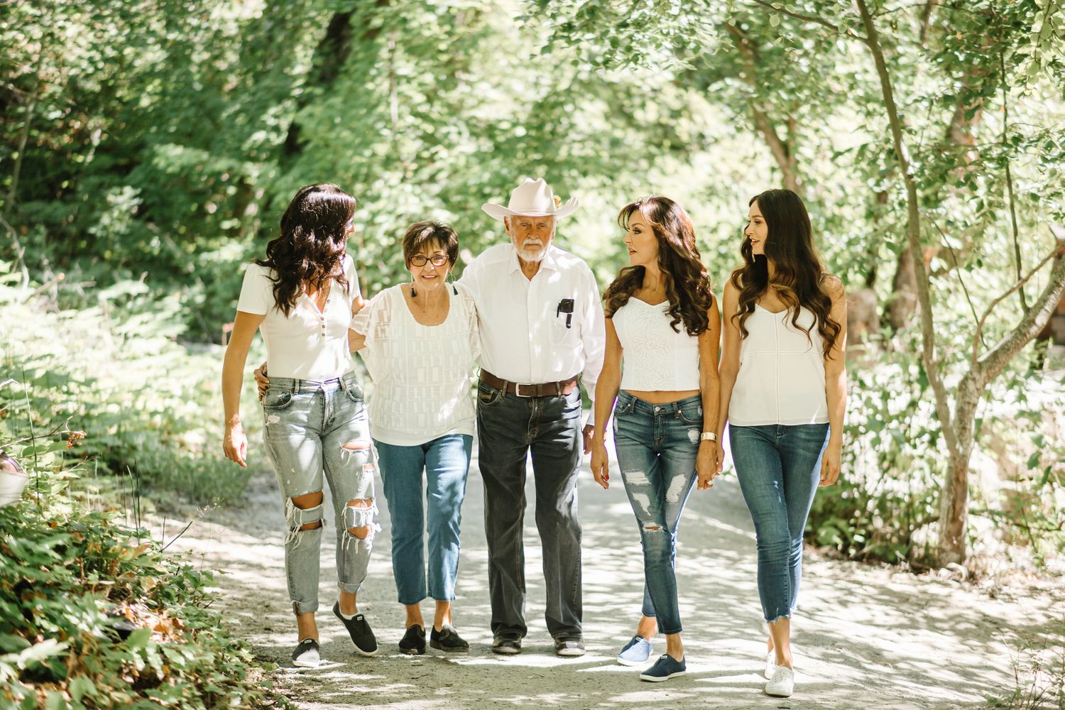 A group walks together along a sunny woodland path on a bright summer day.