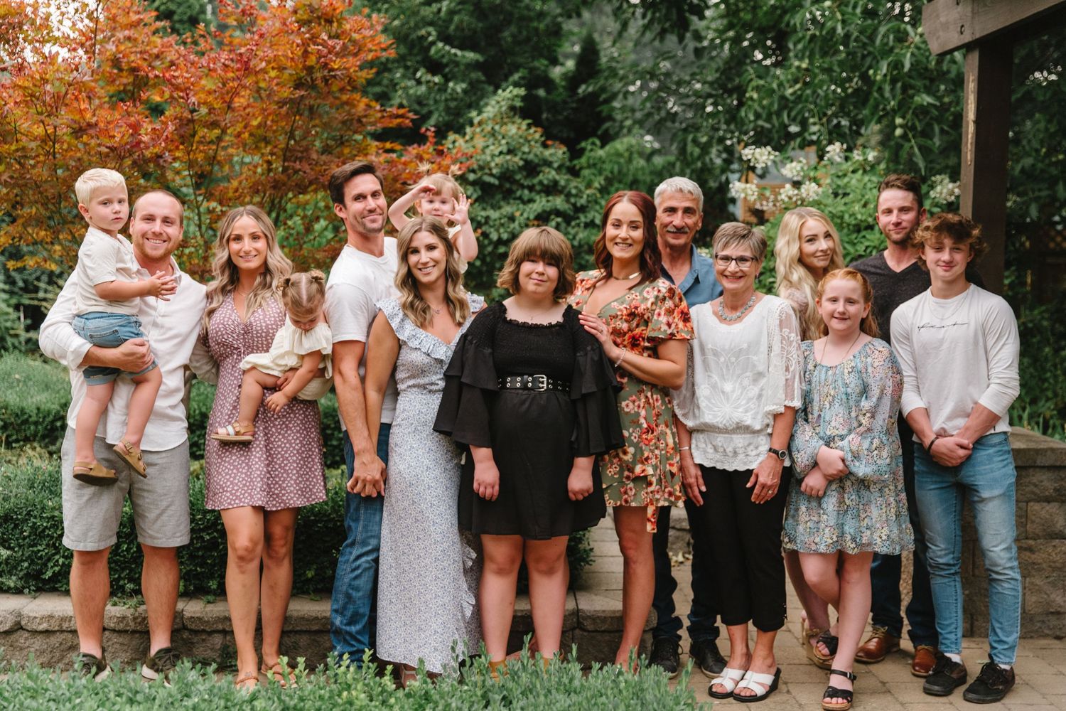 Large group photo of friends and family gathered outdoors in summer attire.