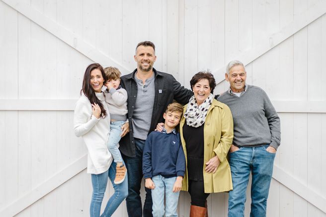 Multi-generational family poses together against white wall background.