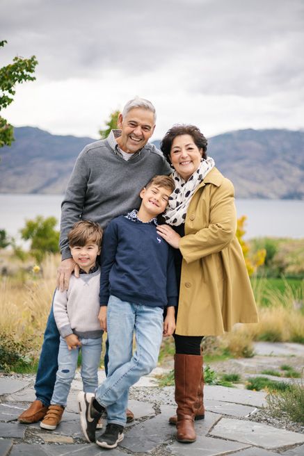 A family shares tender moments together outdoors with mountains in the background.