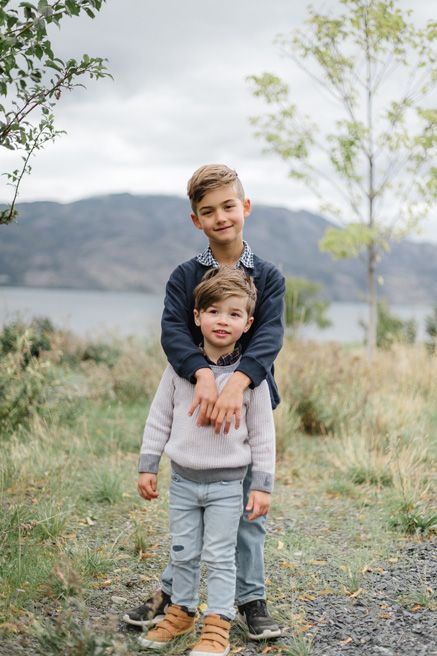 Candid family moments captured on a rocky path with mountain scenery in the background.