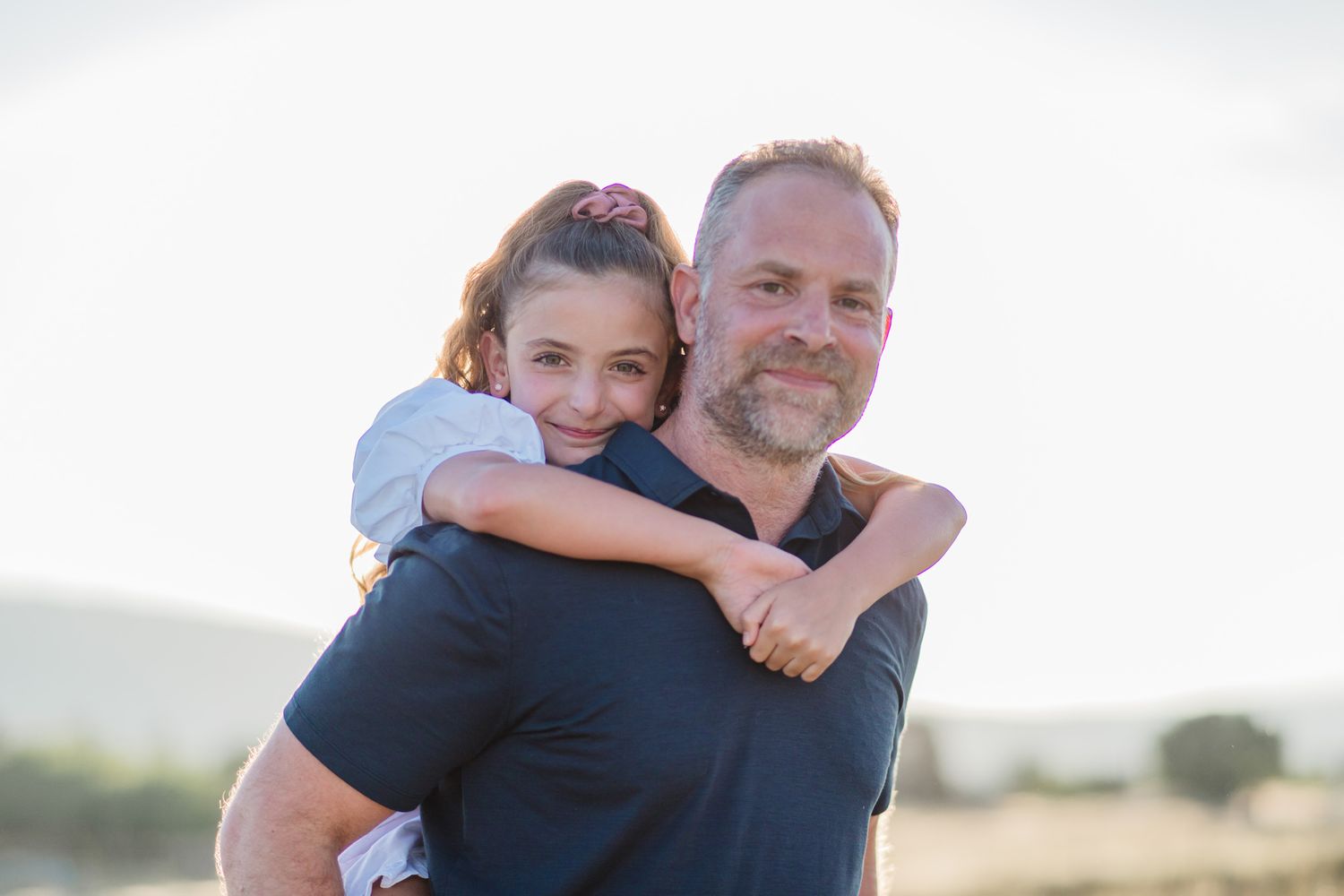 Casual outdoor family portraits with natural sunlight and white background.