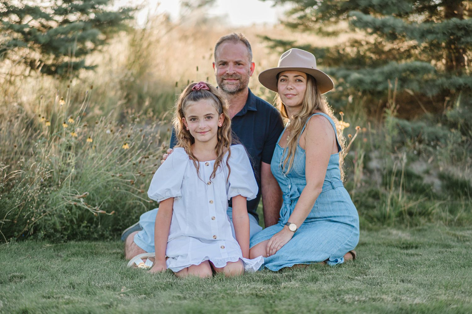 Family members relax together on grass with mountain scenery in the background.