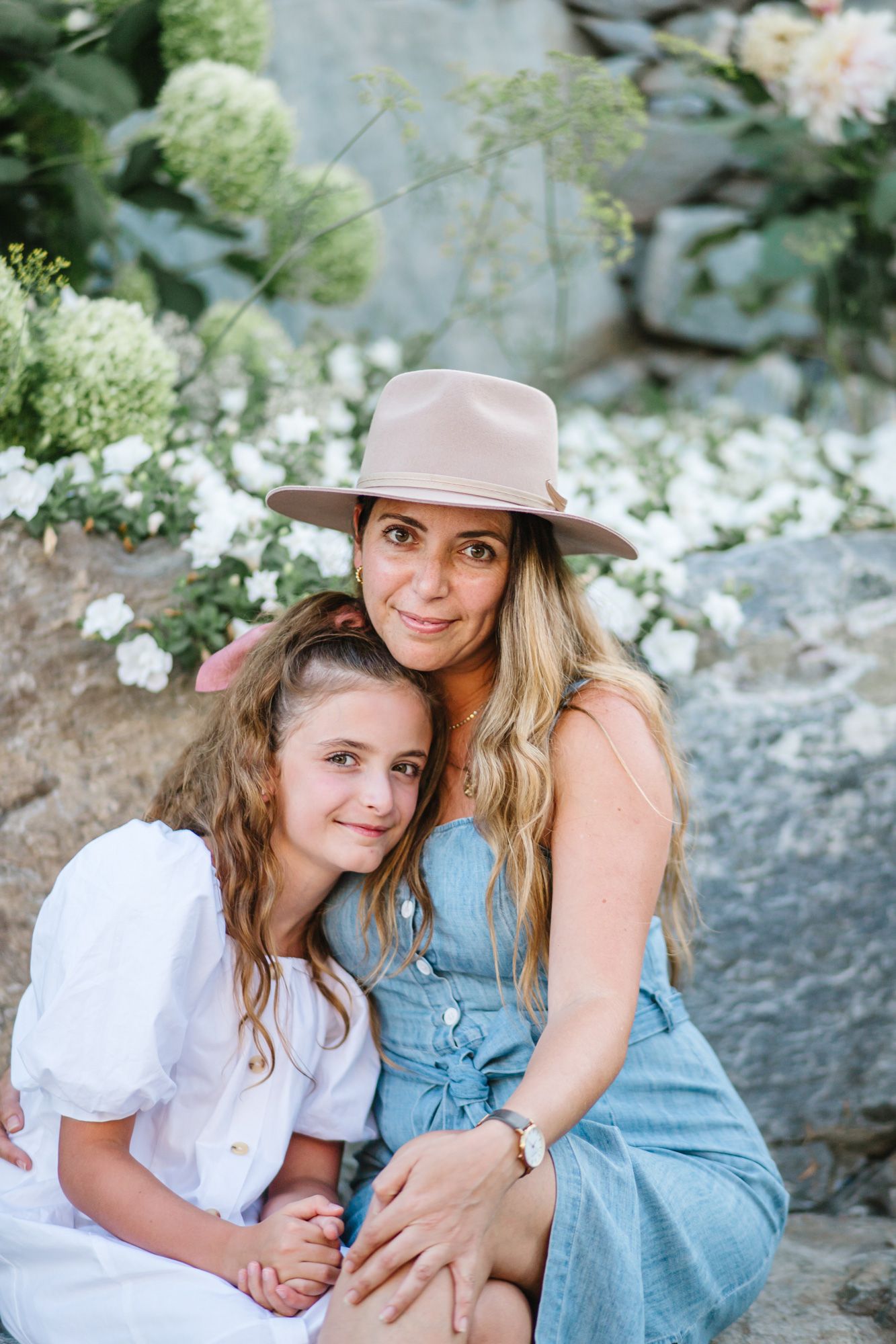 Mother and daughter share intimate moments while sitting on rocks outdoors.
