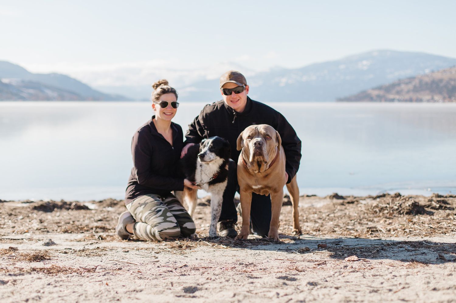 Family and their dog enjoy time together on a rocky beach with mountain views.