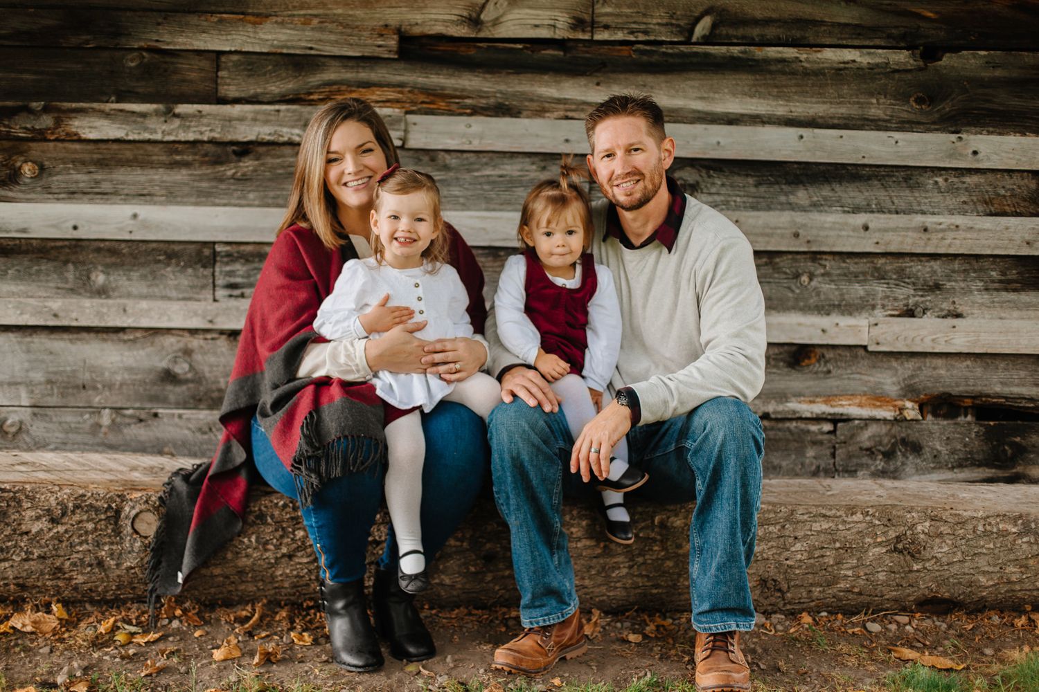 Family members sit casually on rustic wooden bleachers during photo session.