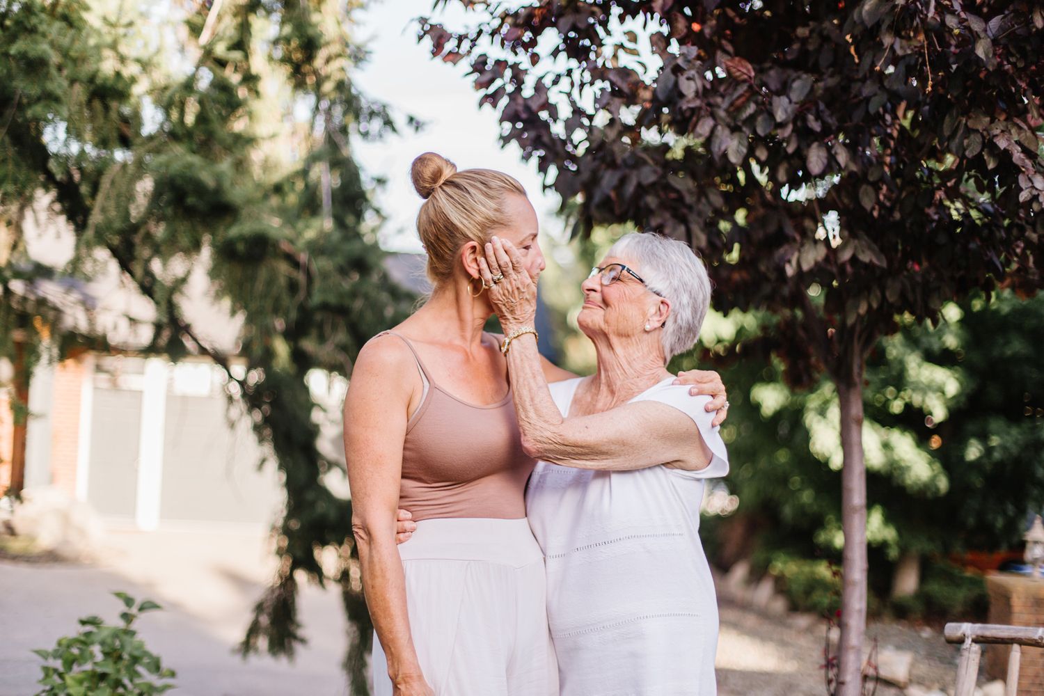 Three women pose together outdoors under trees during summer photoshoot.
