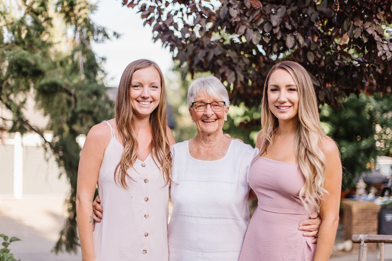 Three women smile together during outdoor family portrait session.