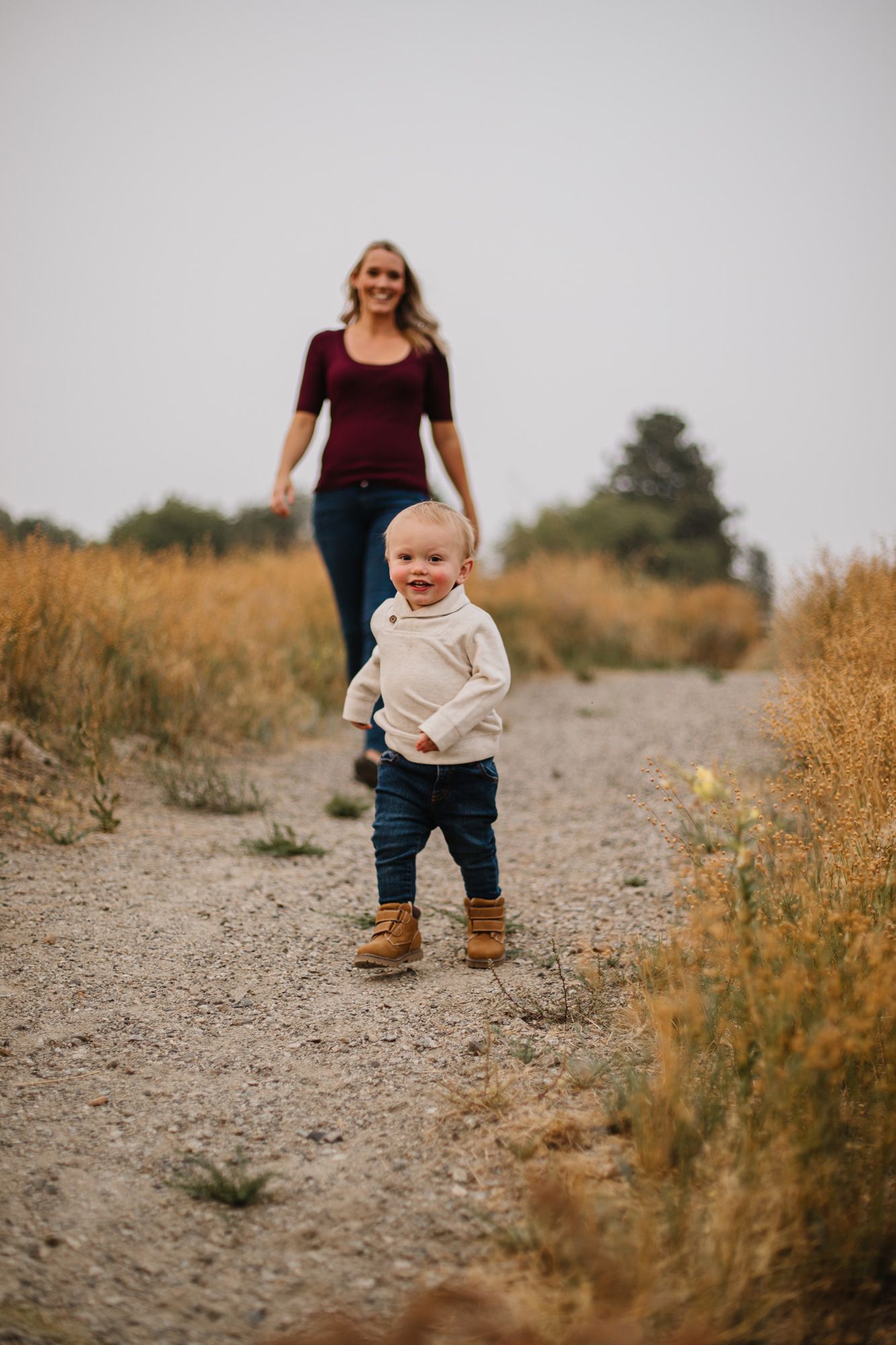 Small child takes first steps on rocky path during outdoor photoshoot.