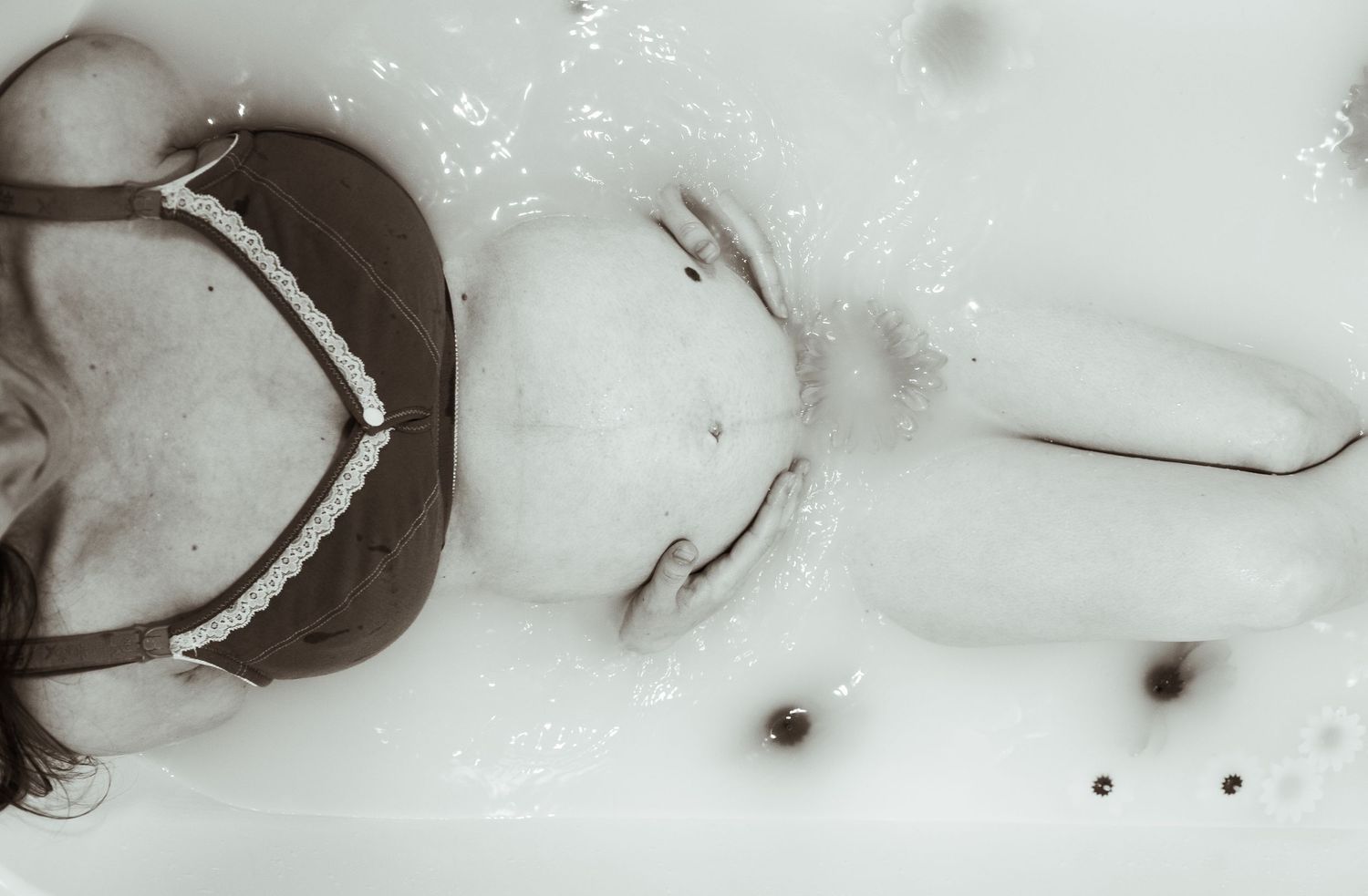 Artistic black and white photo of woman relaxing in bathtub water.