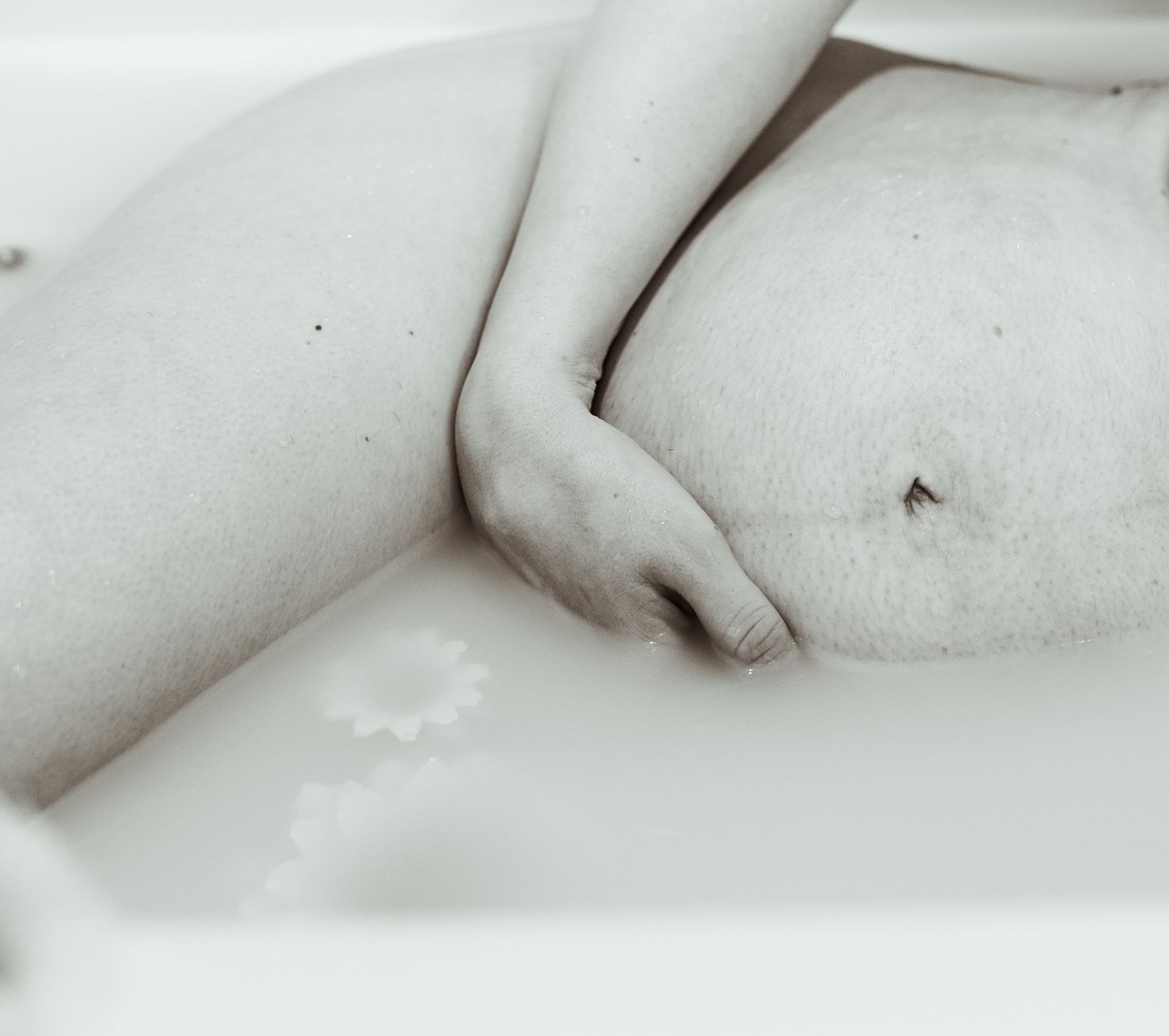High key black and white photo showing silhouette of person resting in bathtub.