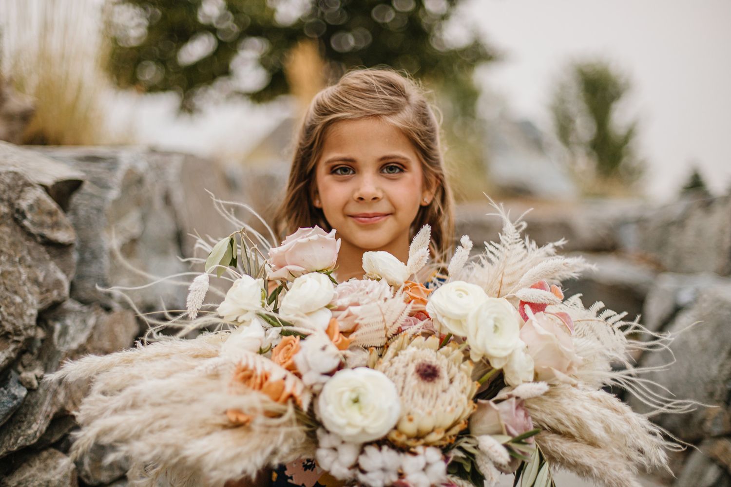Close up portrait with large bouquet of blush and cream colored flowers.
