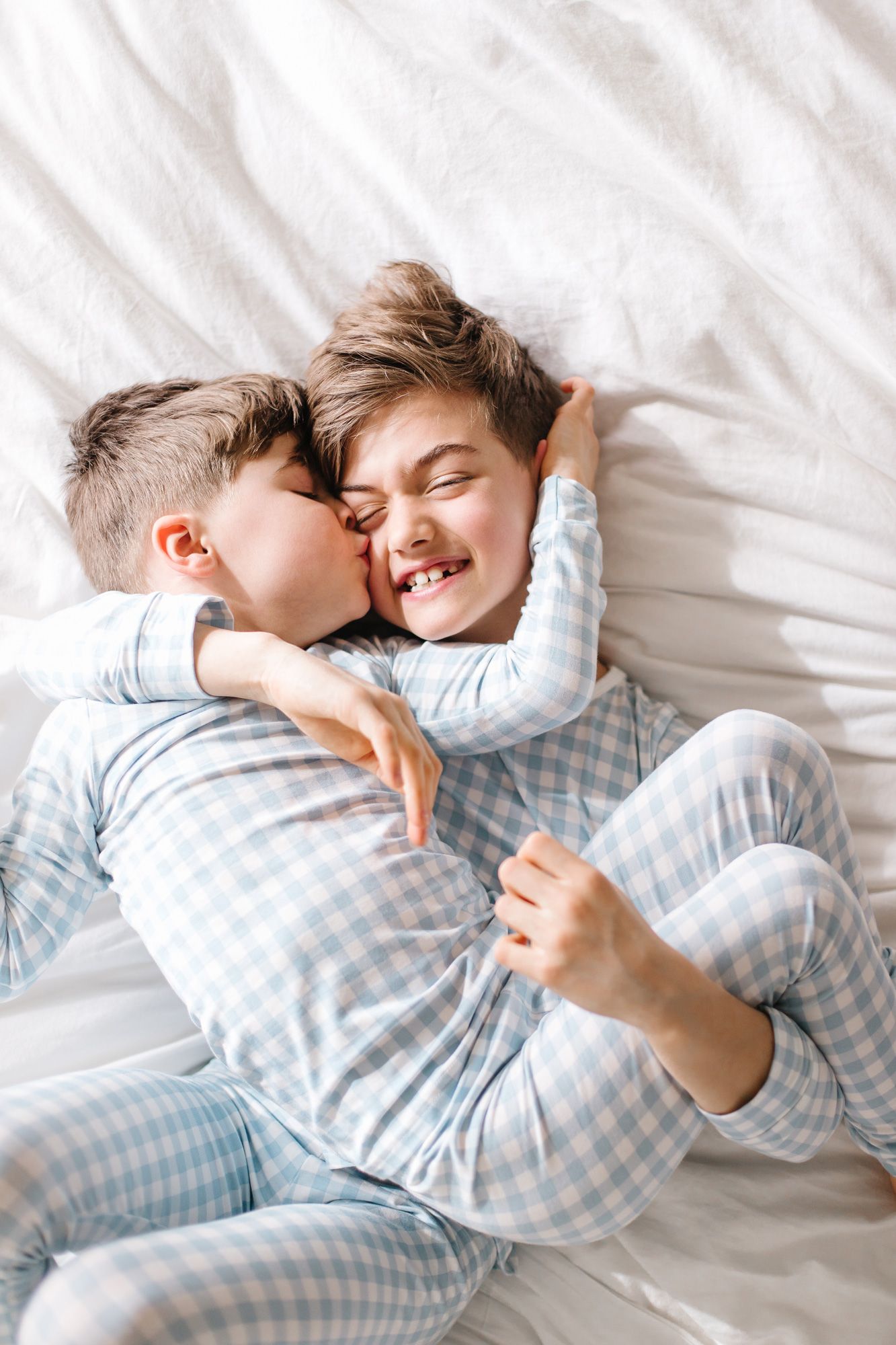 Intimate lifestyle photos of cuddling and laughter in matching blue gingham sleepwear.