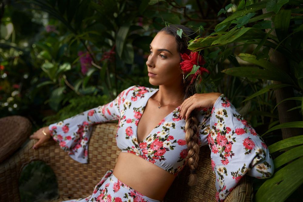 Portrait of a model in a floral crop top against a tropical garden background.