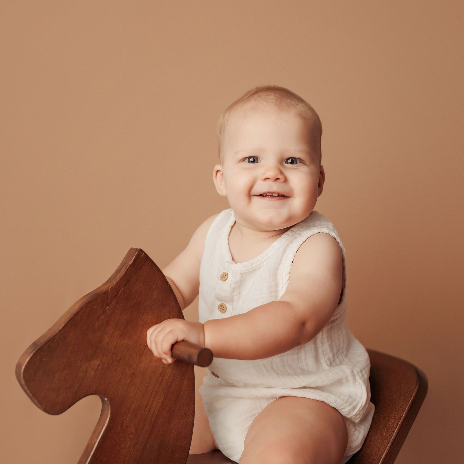 Baby boy riding a toy horse at his milestone photography session in Tulsa,OK