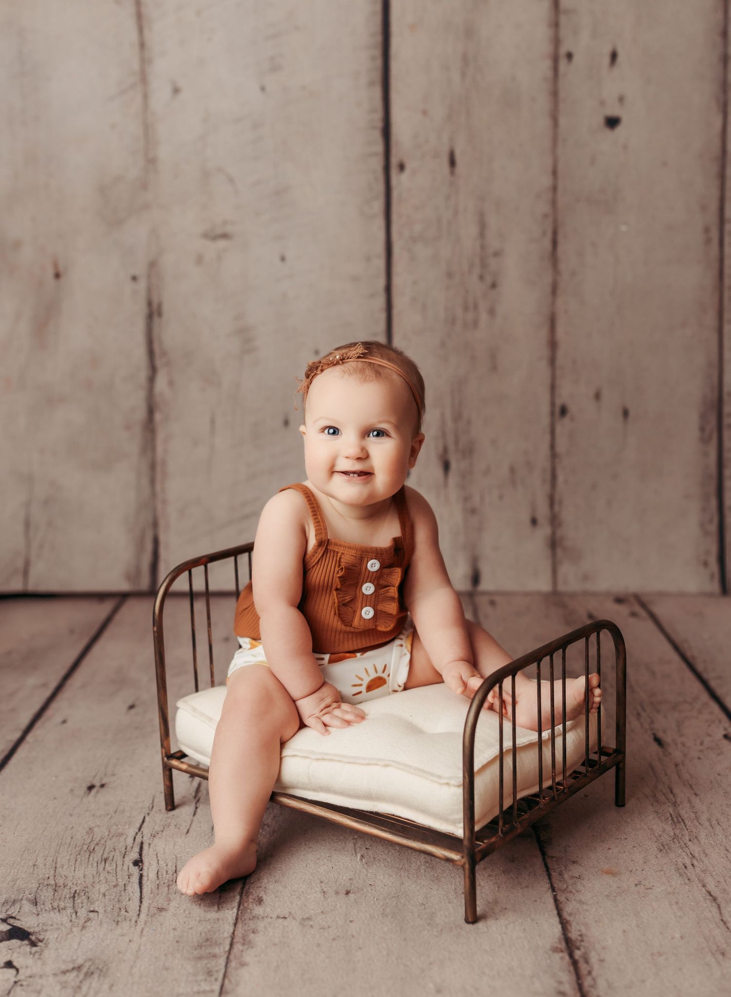 baby girl sitting on prop bed at her milestone photography session in tulsa