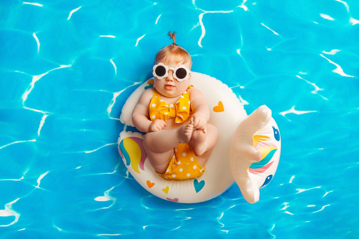 baby girl at her milestone session in tulsa posed in a pool floaty on a water background