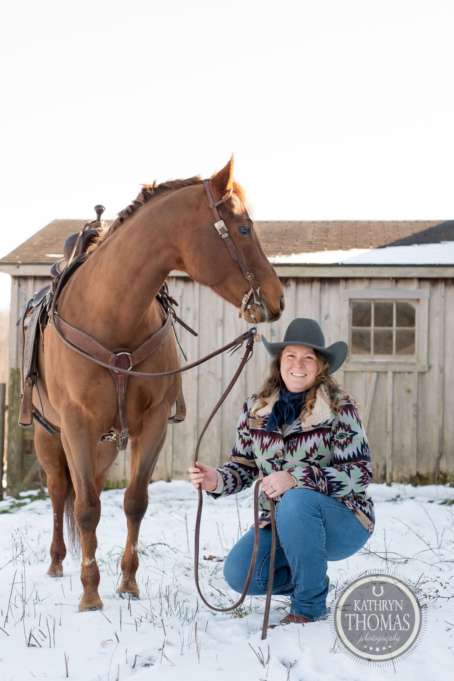 Chestnut horse and handler in western wear pose in snowy winter setting.