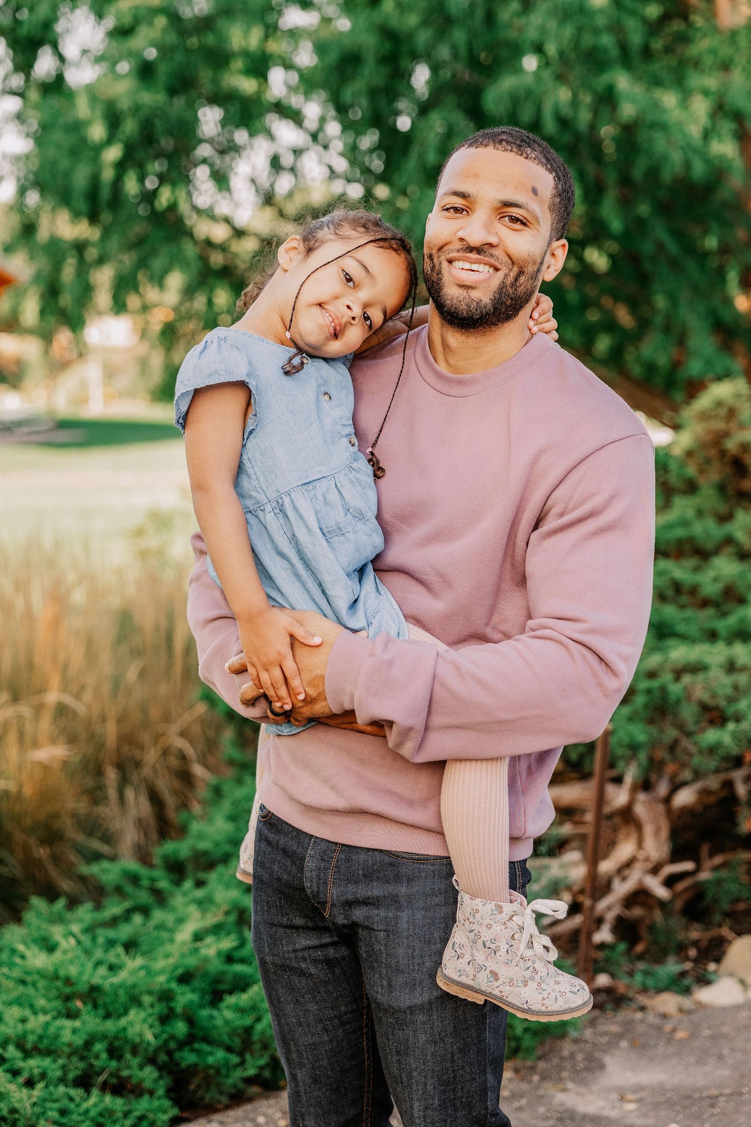 Sweet embrace between parent and child wearing coordinating pink and blue outfits in a garden setting.