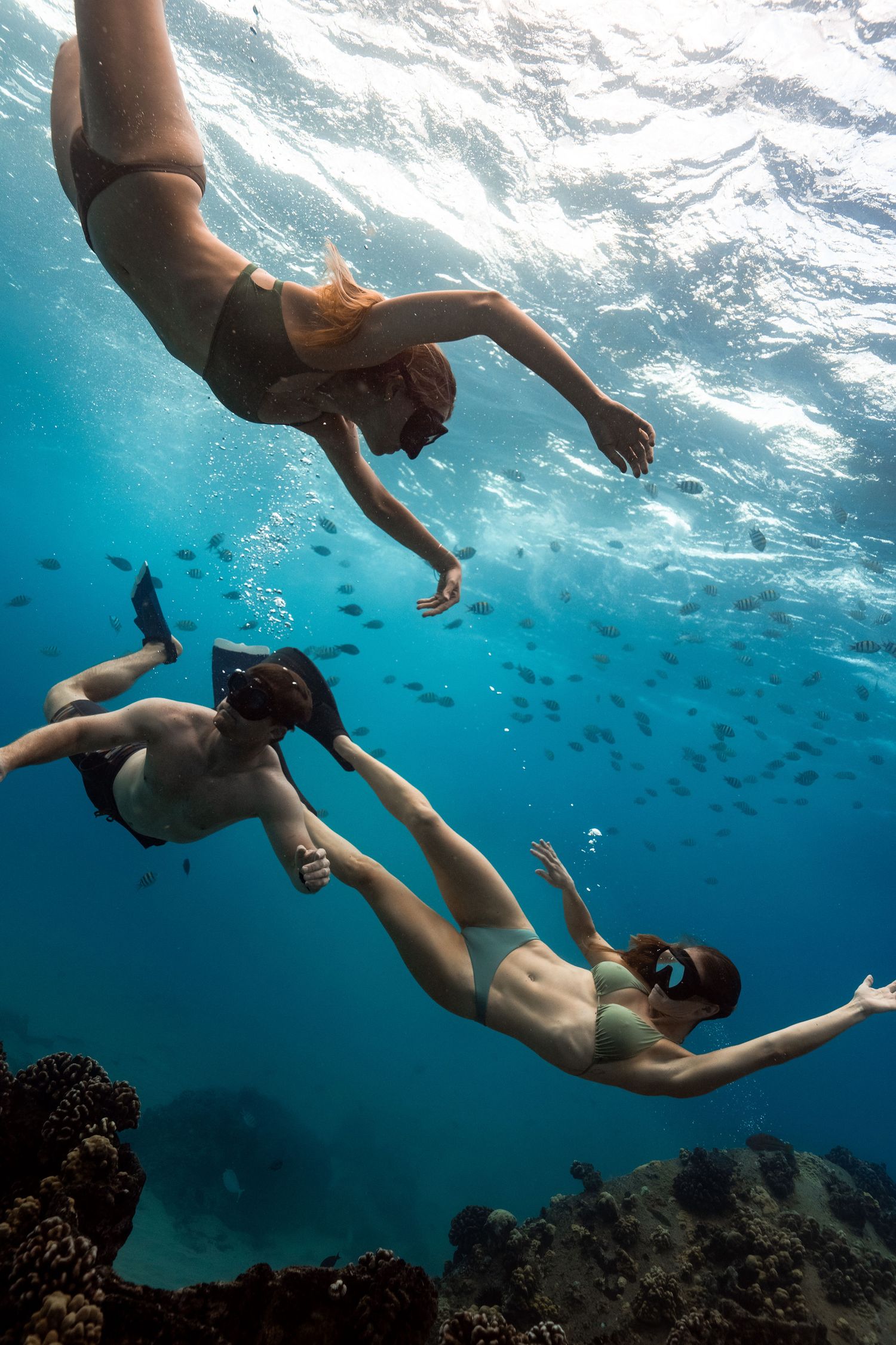 Friends swimming underwater with fish in Hawaii