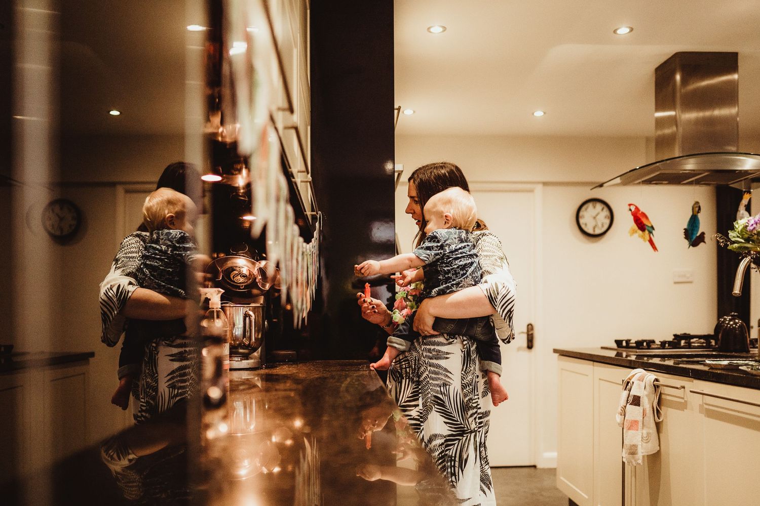 birthday boy being held by his Nanny looking at the photos bunting, their is also a reflection of them in the oven