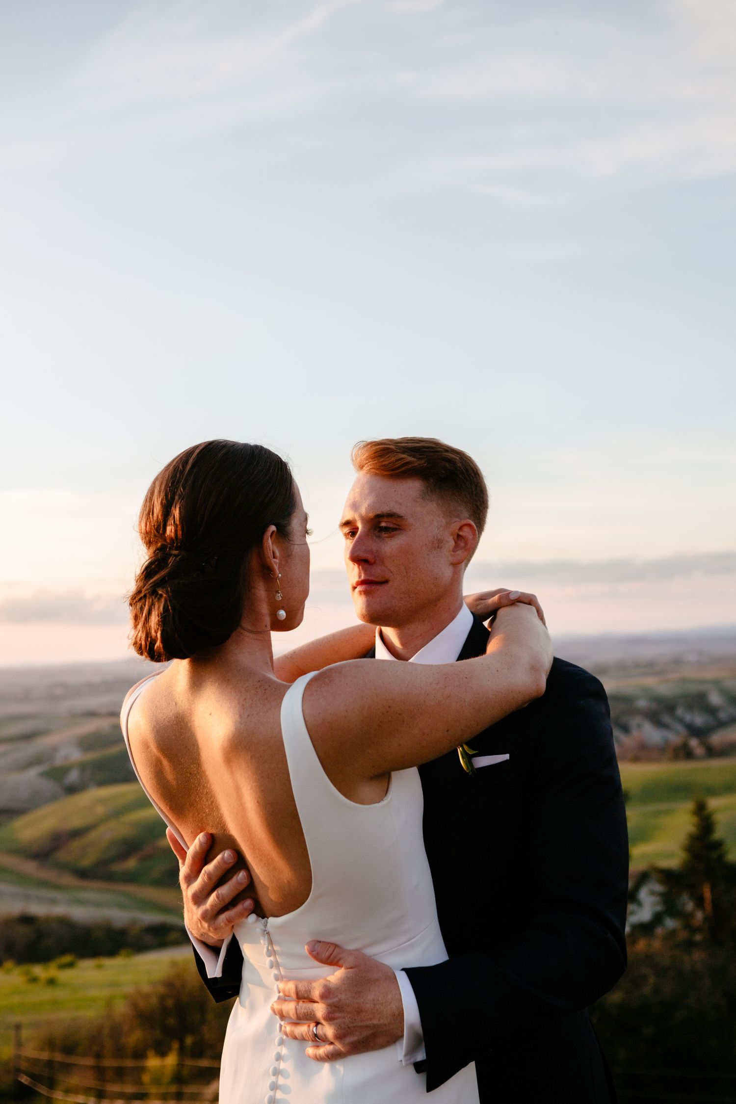 A groom looks lovingly at his bride as the sun sets at their destination wedding at The Lazy Olive near Siena.