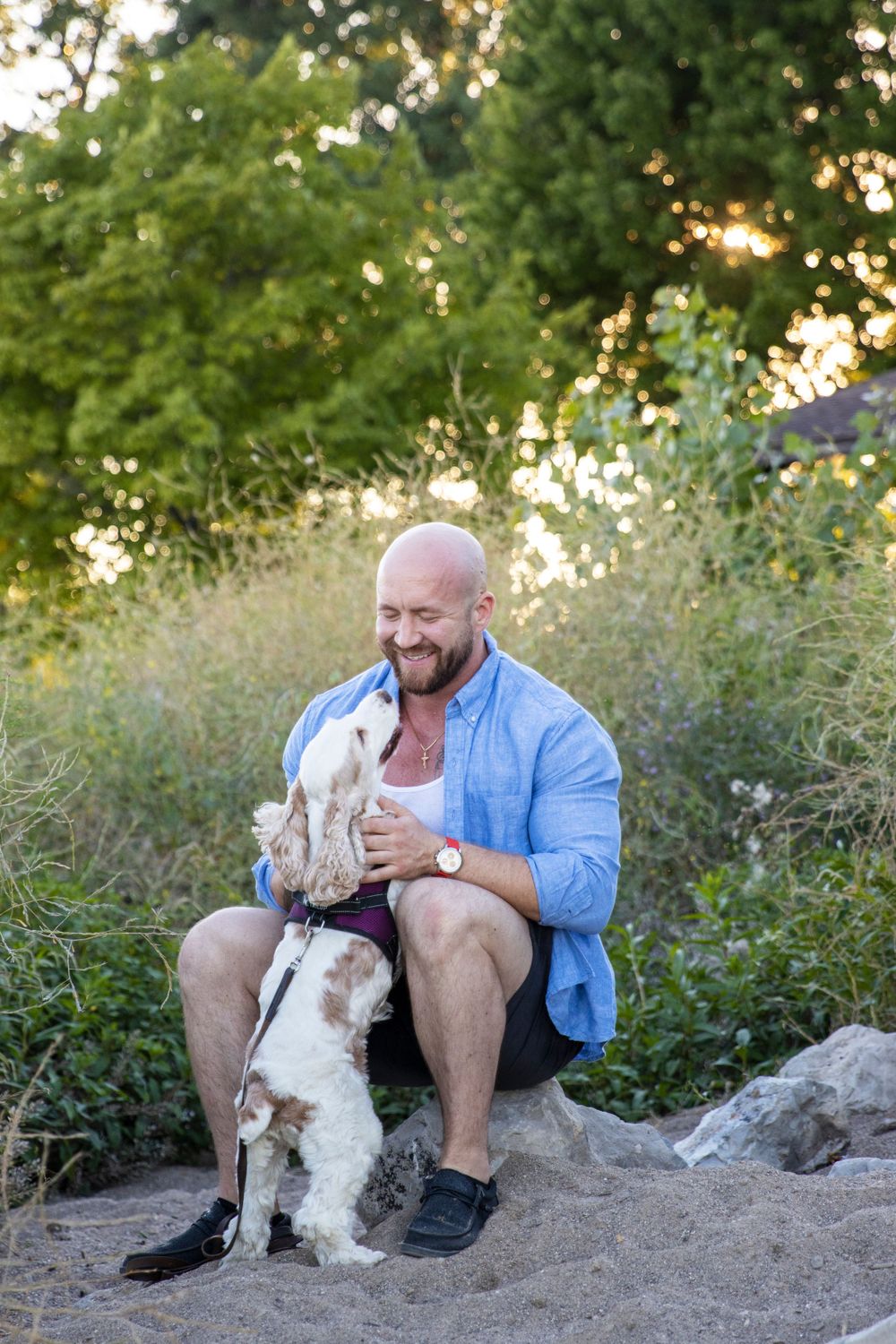 man playing with his dog on the beach of lake saint clair