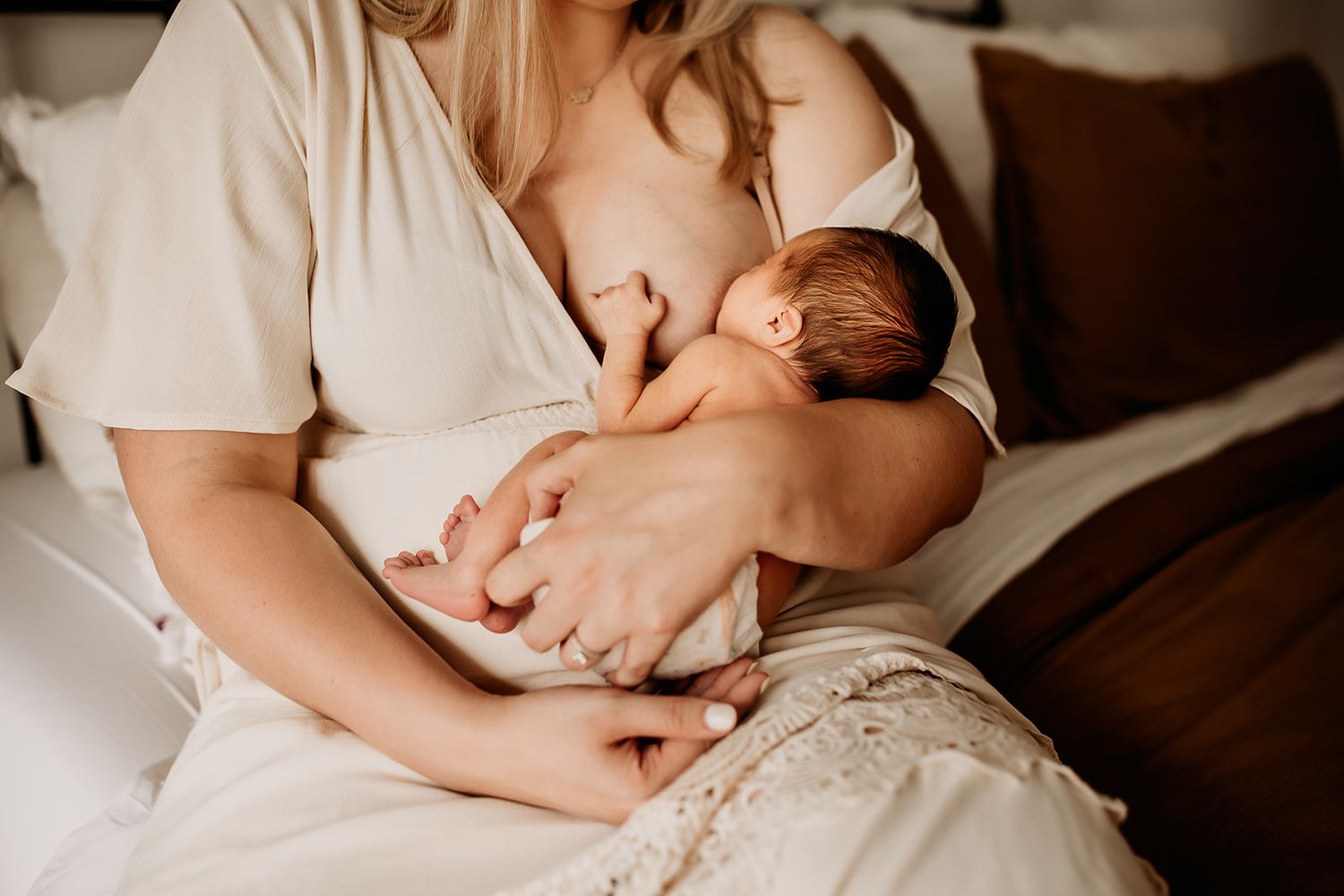 A mother breastfeeding her newborn baby boy during their in home newborn photoshoot.
