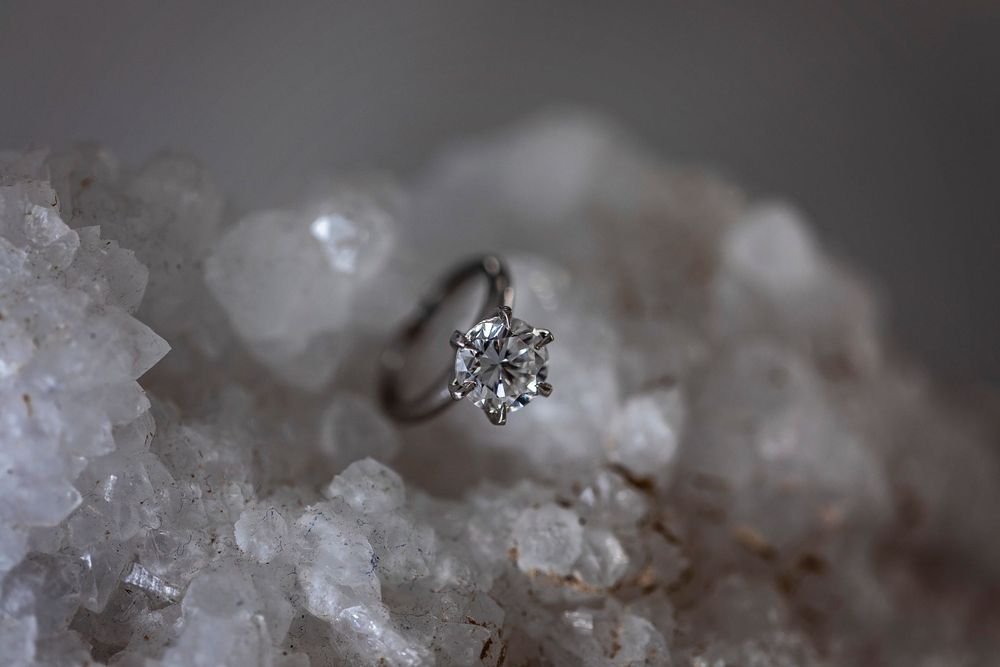 A diamond engagement ring photographed on crystalline white mineral formation.