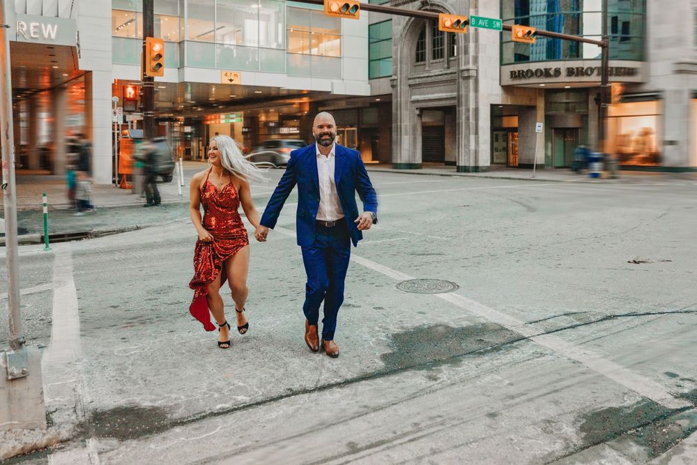A couple walks hand in hand down a city street at dusk.