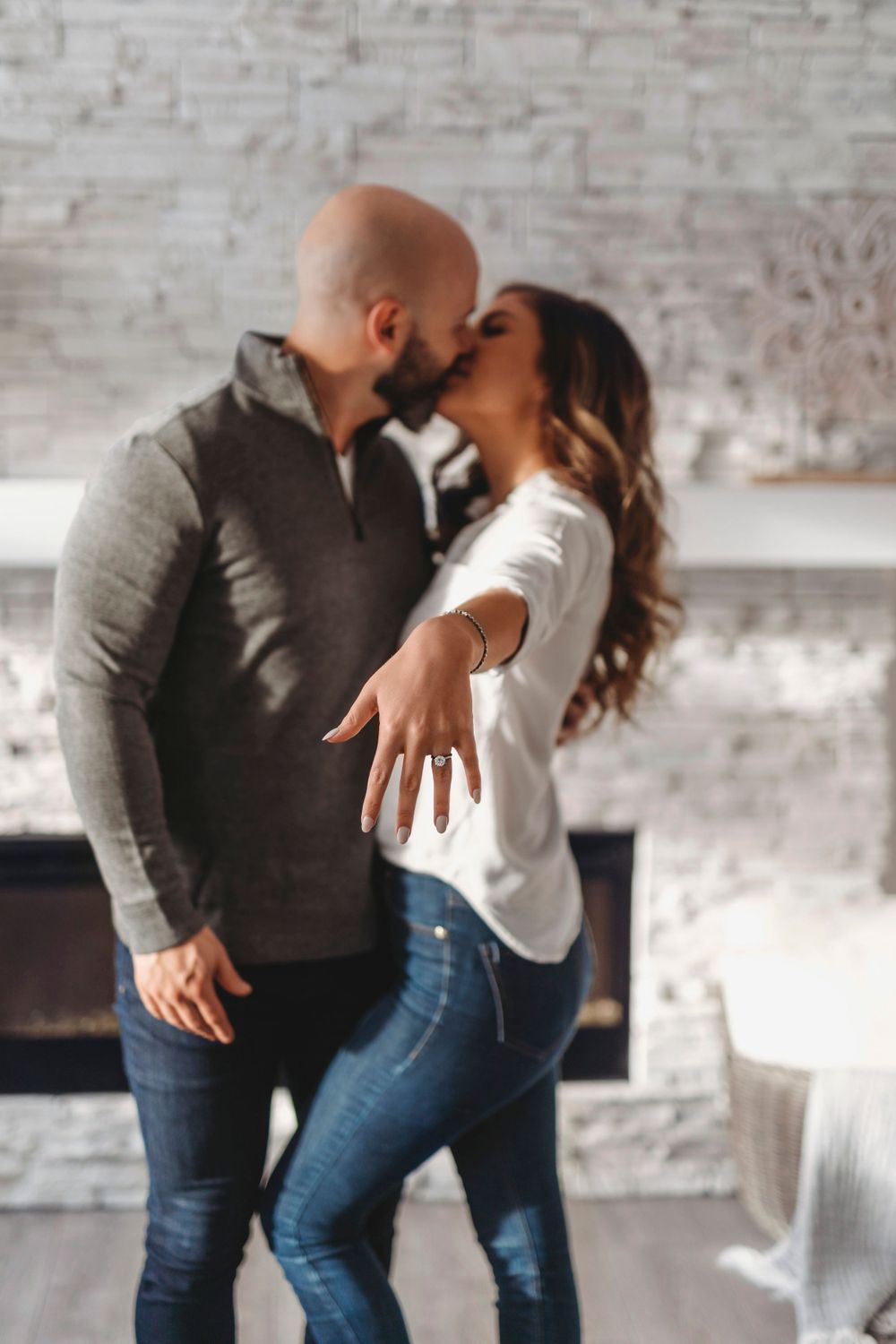 A couple sharing an intimate moment while showing off an engagement ring.