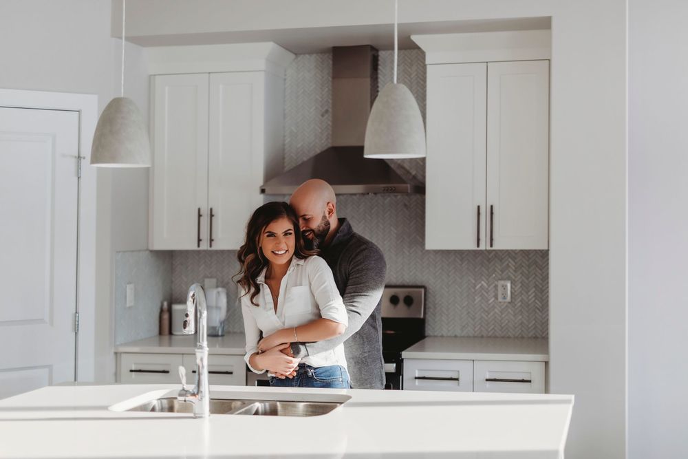 A tender moment shared in a modern white kitchen with pendant lighting.