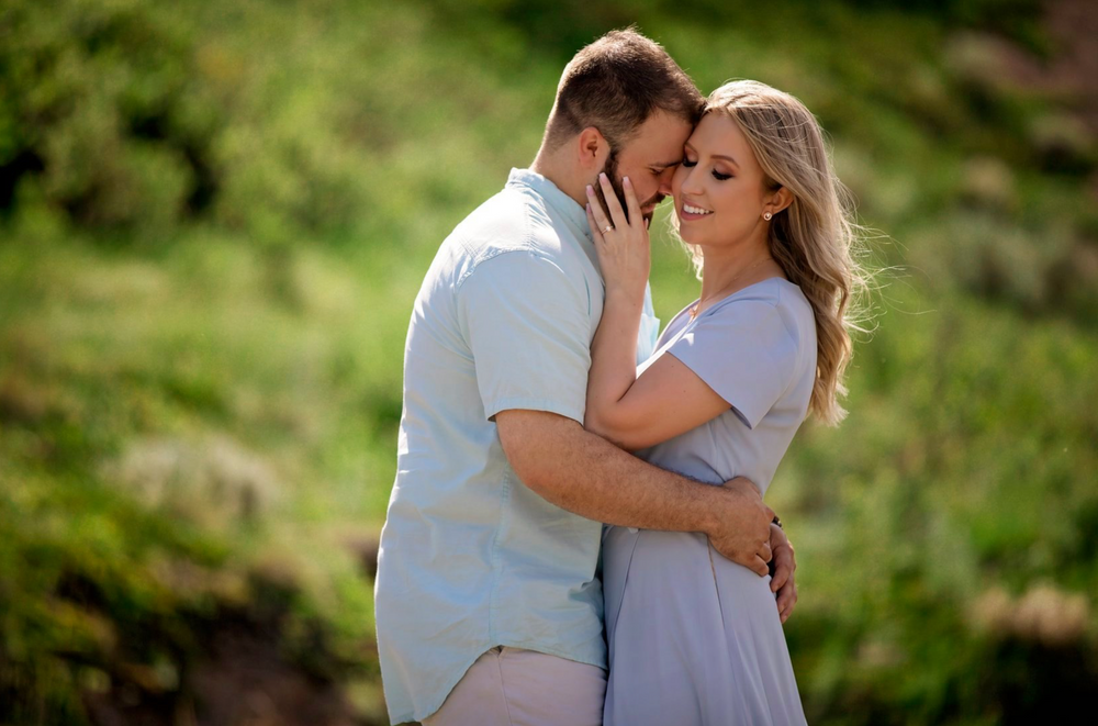Romantic couple embracing outdoors in soft natural lighting.