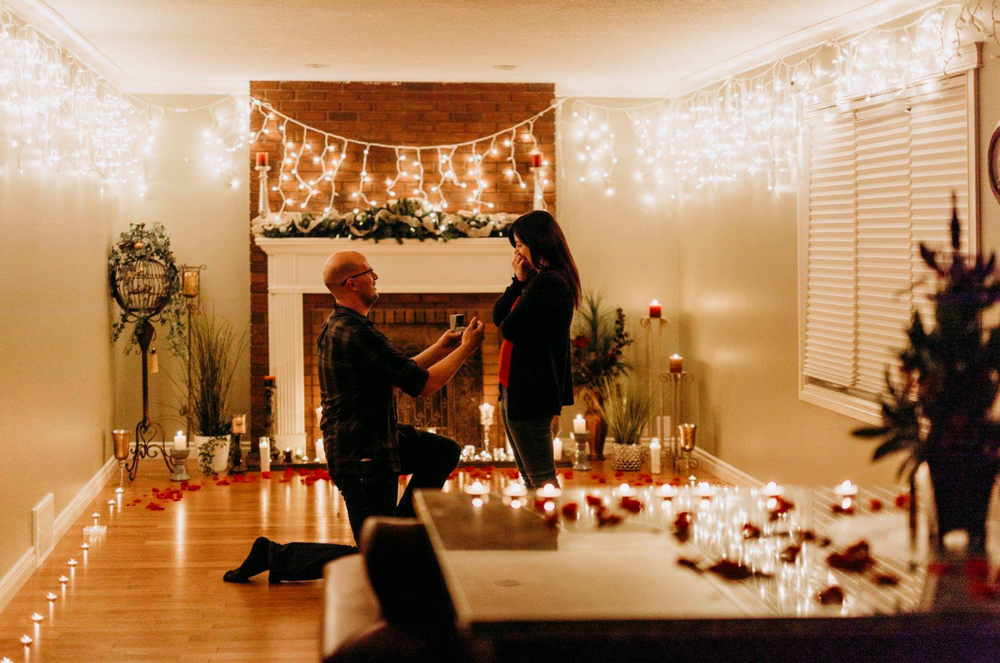 An intimate candlelit proposal scene decorated with string lights and roses.