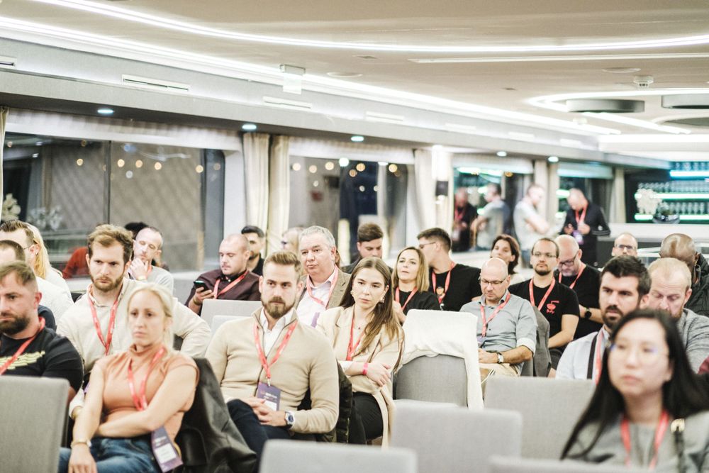 Large audience seated in rows at a business conference or seminar.