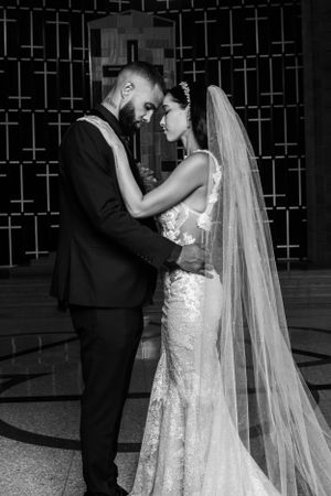 A tender black and white shot of a newlywed couple in wedding attire sharing an intimate moment.