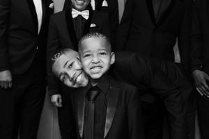 A joyful black and white portrait captures two smiling figures in formal attire at a special occasion.