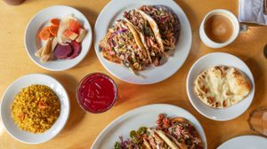 Variety of Mexican dishes and sauces arranged on wooden table.