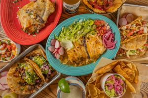 Colorful spread of Mexican food dishes on red and turquoise plates.