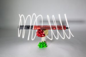 Light painting photography with red and green objects creating spiral light trails.