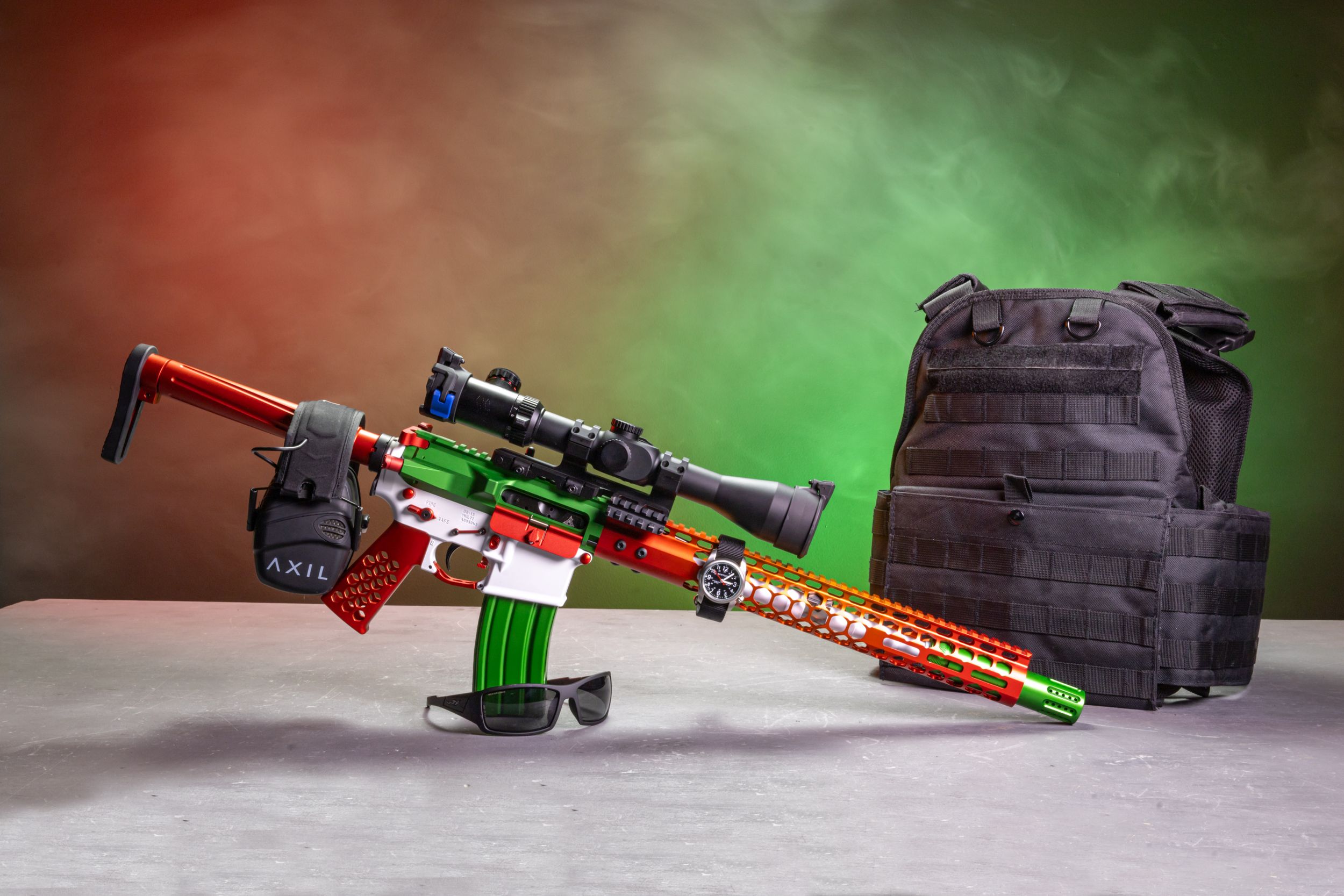 Colorful custom rifle displayed with accessories against dramatic lighting and smoke effects.