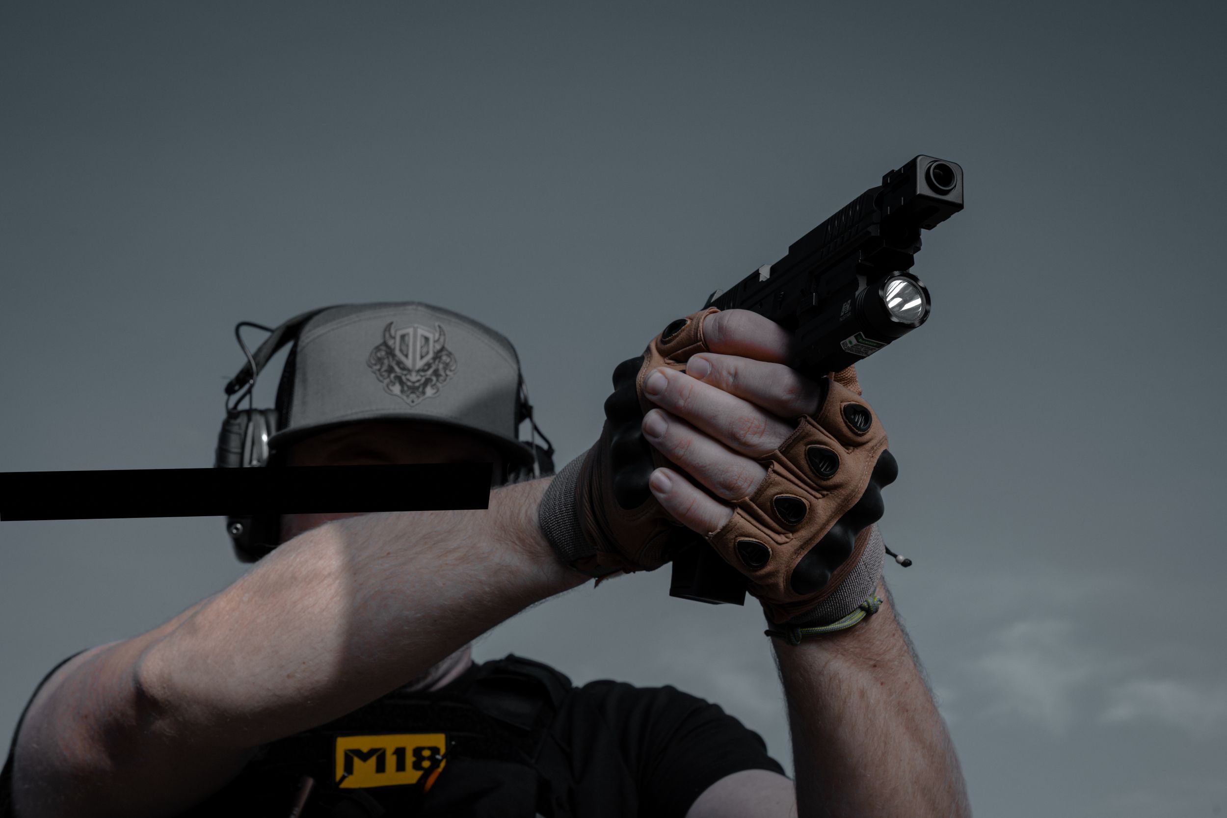 Hands holding tactical gear against dark background with light painting effects.