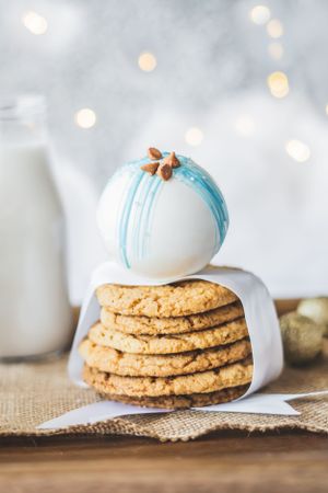 Stack of golden cookies topped with a blue and white decorated chocolate truffle against a bokeh background.