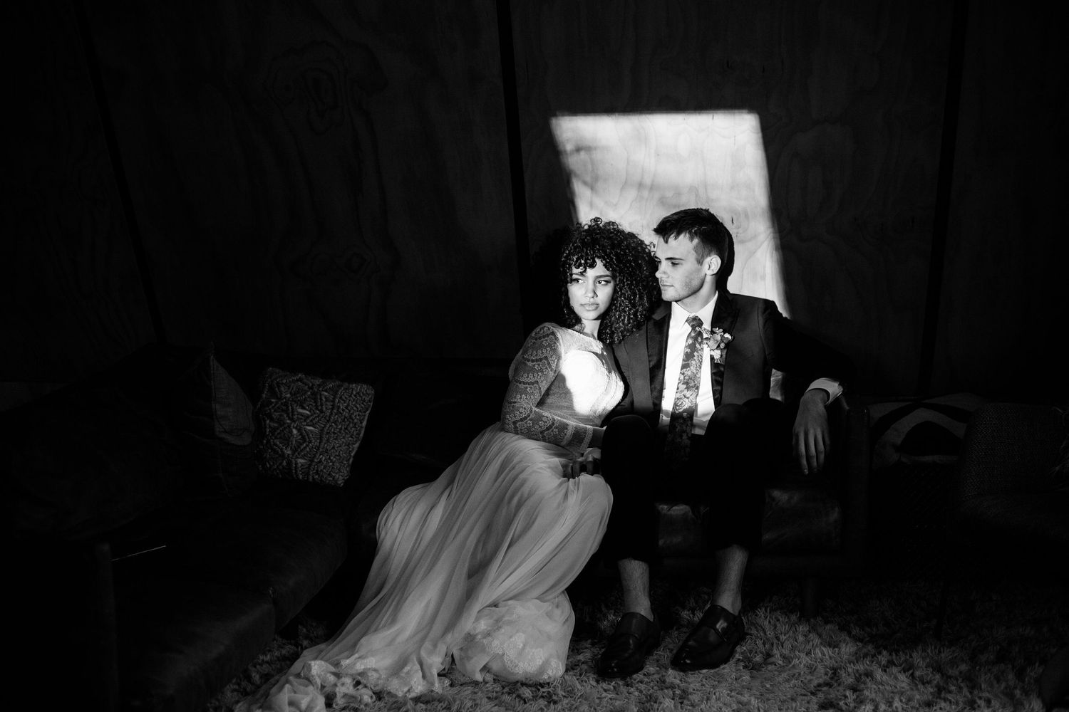 A romantic black and white portrait of a couple sitting together in formal attire.