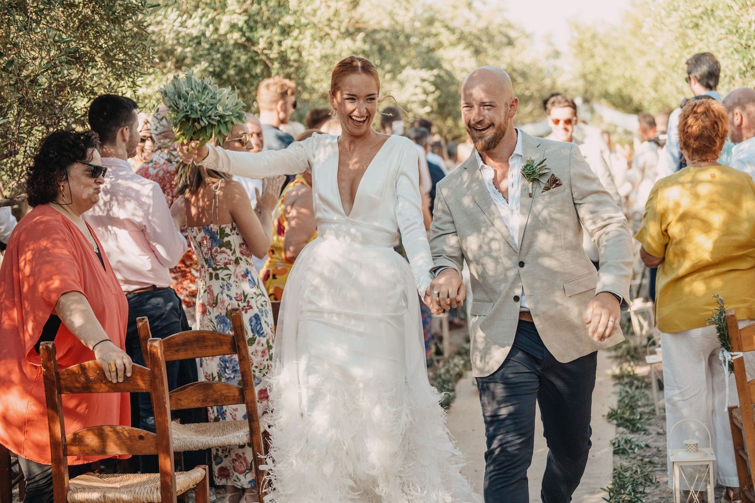 Wedding celebration with guests throwing confetti during recessional under sunny skies.