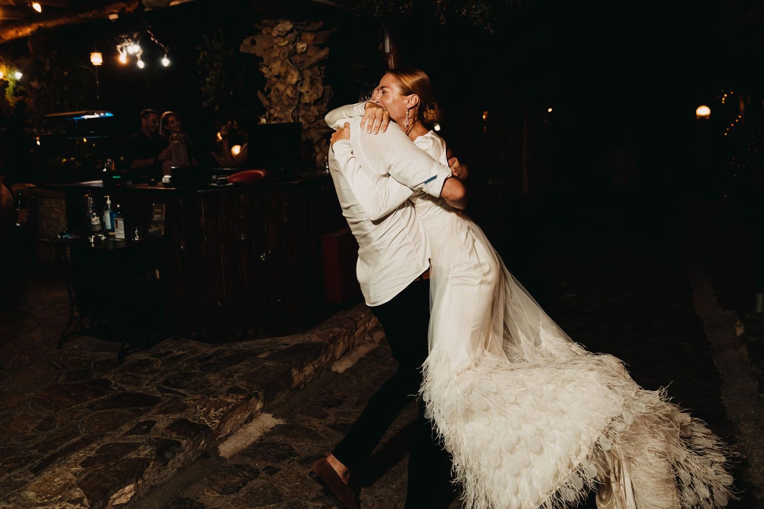 Wedding couple dips dramatically during evening dance with flowing white dress.