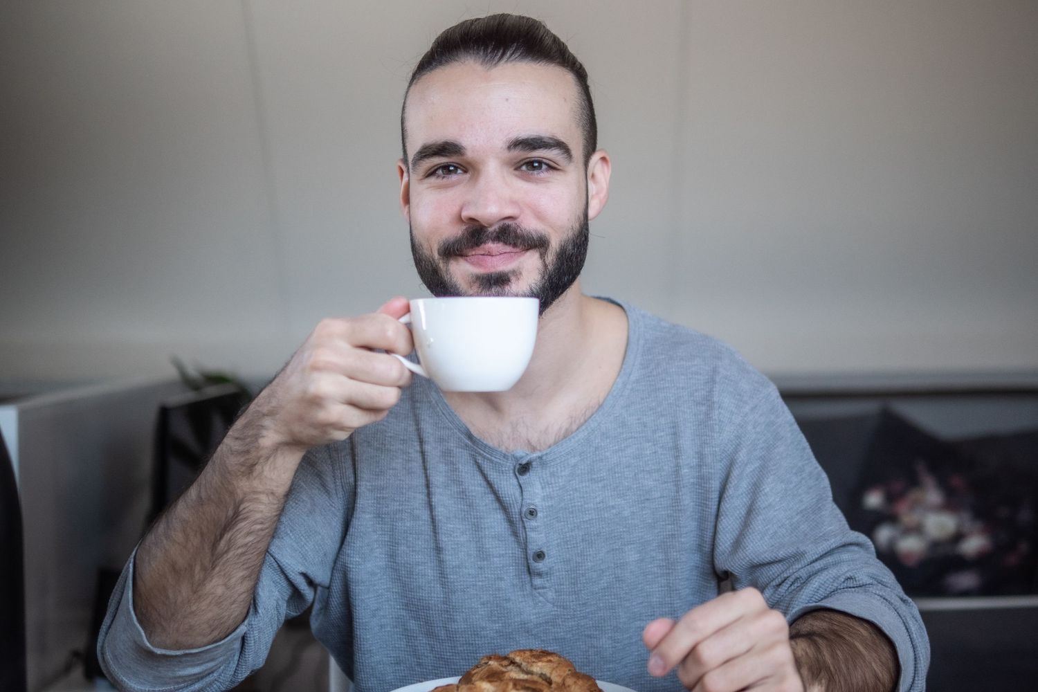 Small business owner smiling and sipping on coffee.