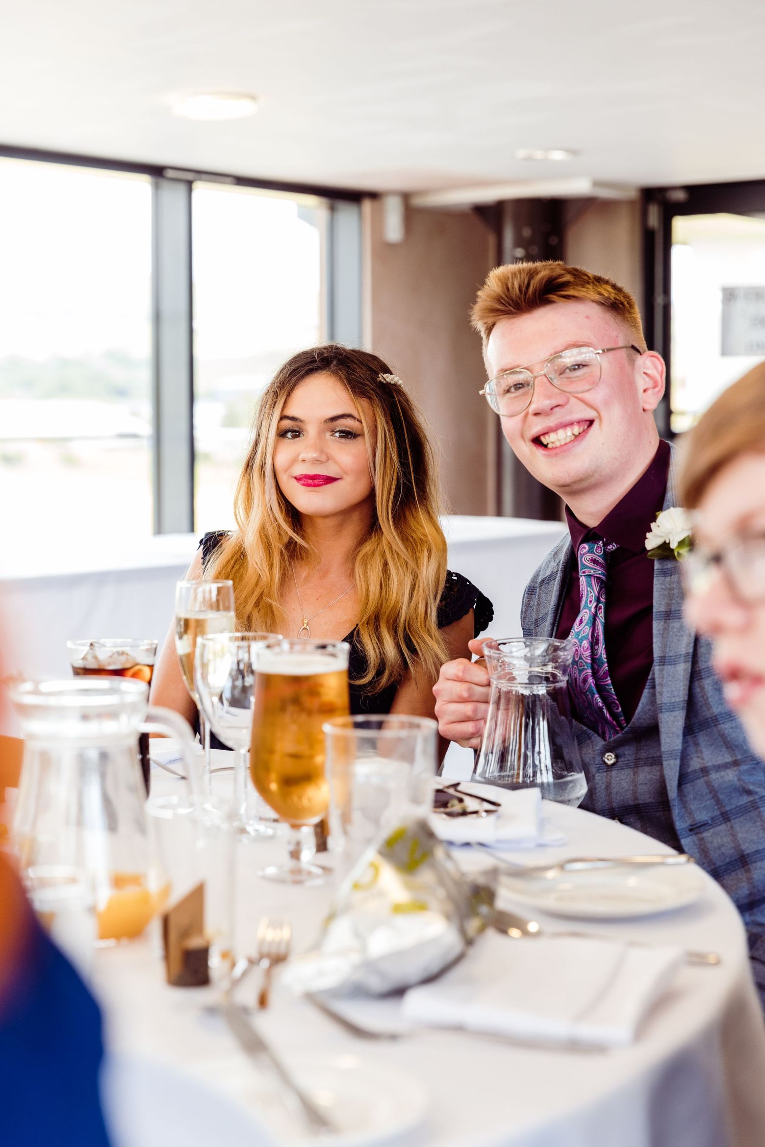 Elegant wedding reception with guests enjoying drinks and conversation at formal dining table.