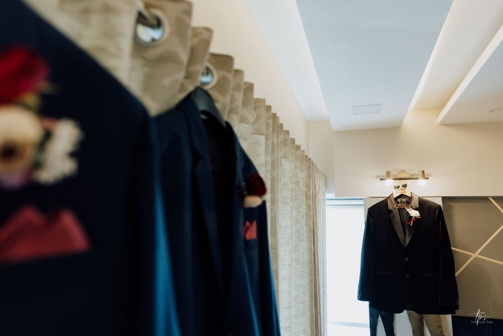 Row of dark suits hanging on clothing rack in preparation room.