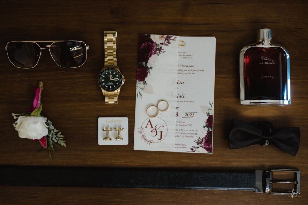 Flat lay of wedding accessories including rings, invitations and glasses on wooden surface.